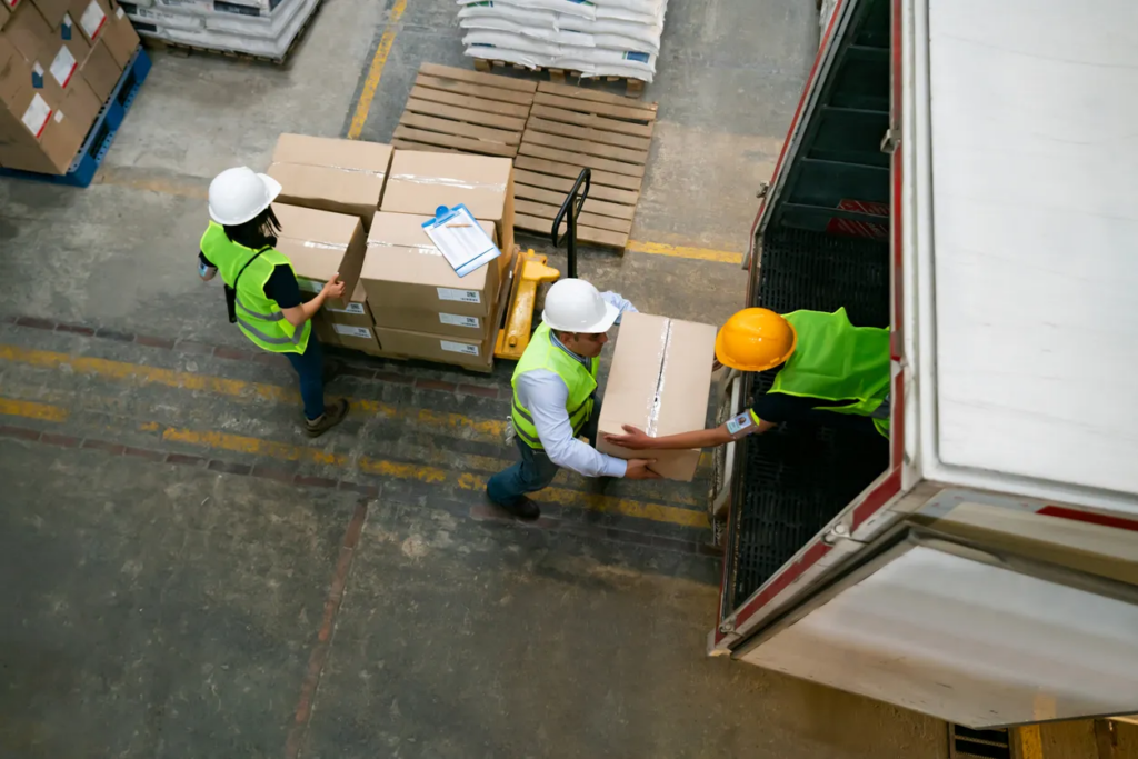 Warehouse workers in safety gear loading boxes onto a delivery truck, illustrating logistics operations for ecommerce shipping solutions in Australia.